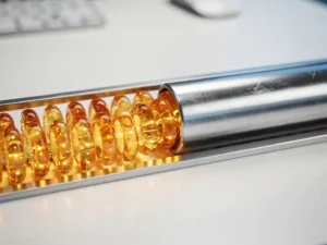 Glowing amber code capsules merging into a silver pipeline on a brushed metal desk, symbolizing automated data consolidation.